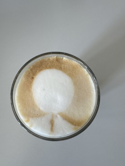 Kaffeeglas von oben mit “Latte-Art”: Kreis, Bogen und etwas, das entfernt a den Fernsehturm in Berlin erinnert. 