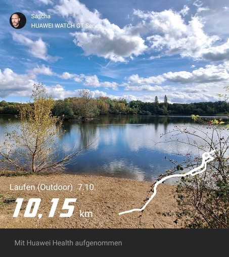 Blick auf einen See. Bewölkter blauer Himmel. Bisschen Gestrüpp. 10km Lauf